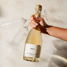 Hand holding BOLLE Blanc de Blancs non-alcoholic champagne bottle for celebration toast, best NA sparkling wine